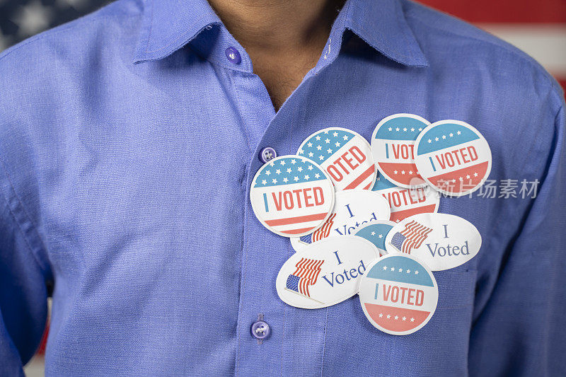 Close up of multiple I Voted tags on blue shirt - Concept of US election voter fraud by放置多个投票贴纸